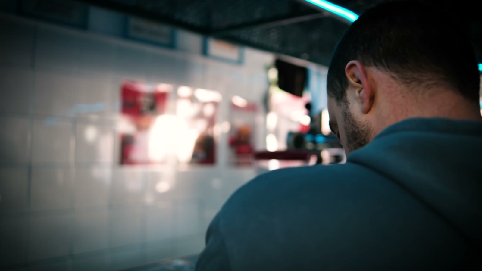 A cook seen from behind in El Barrio's teal-lit kitchen